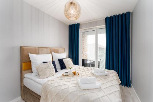 Schlafzimmer mit einem großen Bett und blauen Vorhängen in der Unterkunft Błękitna Perła by Perłowa Przystań Rent in Kołobrzeg