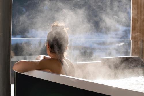 a woman in a bathtub with steam coming out of it at Latemar - Hotel Suites Spa in Soraga