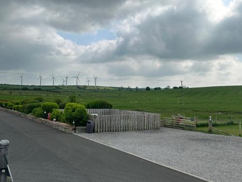 a fence on the side of a road with wind turbines at Luxury Lake District Holiday Lodge-Sleeps 4 in Cockermouth