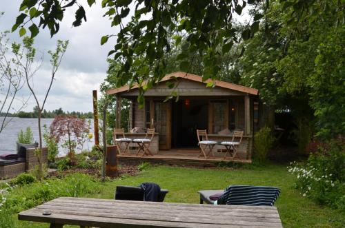 a small cabin with a table and chairs in the grass at Luxury Experience in Off The Grid Lodge at an Amazing Lake Vinkeveense Plassen in Vinkeveen