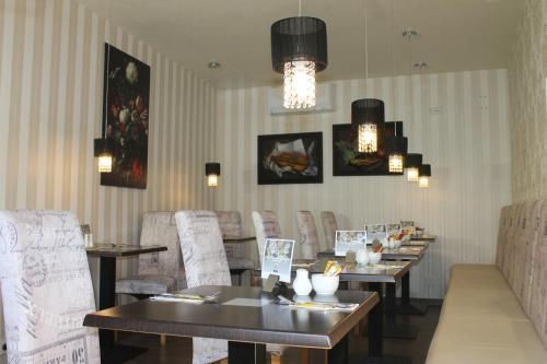 ein Esszimmer mit Tischen und Stühlen und Kronleuchtern in der Unterkunft Boulevardhotel Sängerstadt - alle Zimmer klimatisiert in Finsterwalde