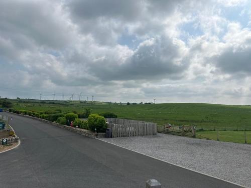 an empty road with a fence and a field at Luxury Lake District Holiday Lodge-Sleeps 4 in Cockermouth