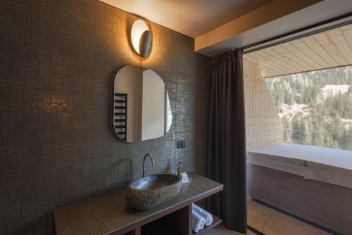 a bathroom with a sink and a mirror at Latemar - Hotel Suites Spa in Soraga