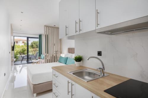 a kitchen with a sink and a living room at Greek Rooms 1 in Kallithea Halkidikis