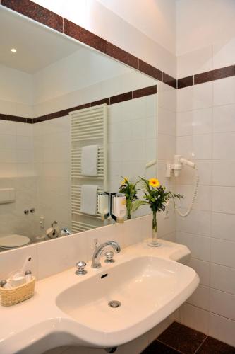 a white bathroom with a sink and a mirror at Hotel Fürst Bismarck in Hamburg