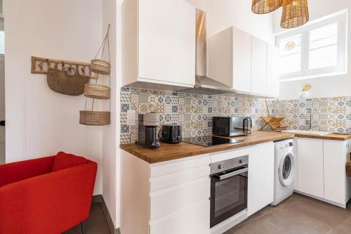 une cuisine avec des placards blancs et une chaise rouge dans l'établissement Superbe logement à 5mins des plages, proche Palais, à Cannes