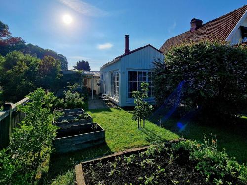 a yard with a blue house and some plants at Charmant hus med bastu och braskamin in Alingsås