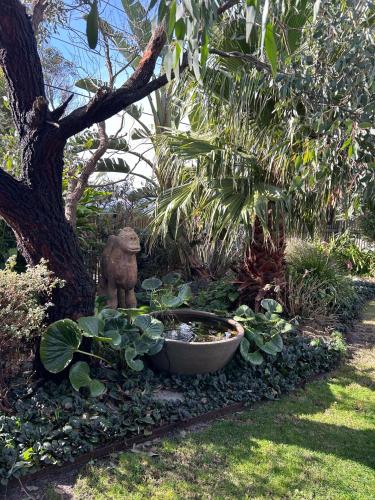 a garden with a bird bath and a statue next to a tree at Jan Juc Garden Sanctuary Steps from the Surf in Torquay