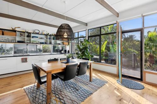 a kitchen with a wooden table and black chairs at Jan Juc Garden Sanctuary Steps from the Surf in Torquay