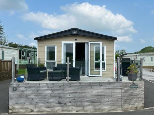 a tiny house with a porch and chairs on it at Luxury Lake District Holiday Lodge-Sleeps 4 in Cockermouth