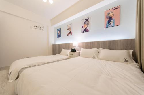 a bedroom with two white beds and pictures on the wall at 宜蘭眾樂樂民宿 in Dongshan