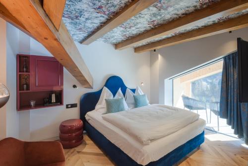 a bedroom with a bed with a blue head board at Latemar - Hotel Suites Spa in Soraga