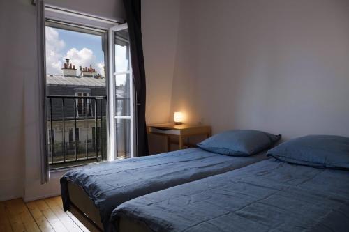 une chambre avec un lit et une grande fenêtre dans l'établissement Charmant appartement au coeur de paris 6ème, à Paris