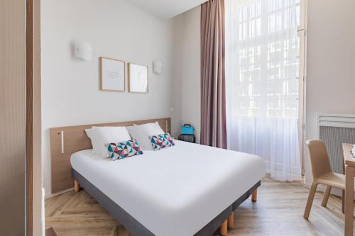 a bedroom with a white bed and a window at Appart’City Confort Reims Centre in Reims