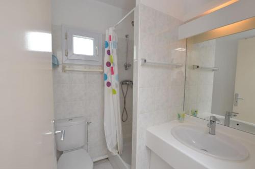 une salle de bain blanche avec des toilettes et un lavabo dans l'établissement Le Baroncelli sur la plage, au Grau-du-Roi