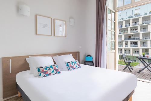 a bedroom with a white bed and a balcony at Appart’City Confort Reims Centre in Reims