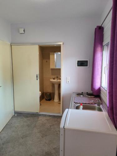 a kitchen with purple curtains and a sink and a bathroom at Pefki Apartment 9 in Artemísion