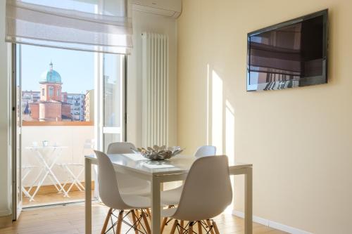 ein Esszimmer mit einem weißen Tisch und Stühlen sowie einem Fenster in der Unterkunft Scandellari Apartments - Porta San Felice in Bologna
