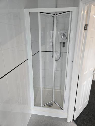 un baño blanco con cabina de ducha de cristal en The Swan Hotel en Milton Keynes
