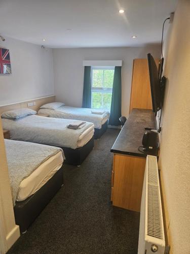 a room with two beds and a desk with a television at The Swan Hotel in Milton Keynes