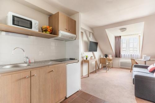 a kitchen with a sink and a microwave in a room at Appart’City Confort Reims Centre in Reims
