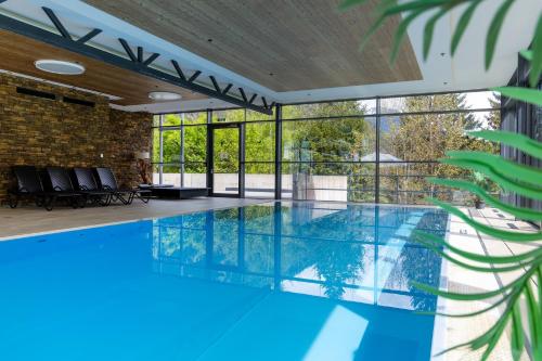 an indoor swimming pool with blue water in a building at DORMERO BeHo Zugspitze in Biberwier