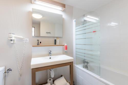 La salle de bains blanche est pourvue d'un lavabo et d'une douche. dans l'établissement Appart’City Confort Reims Centre, à Reims