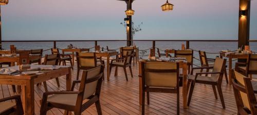 a restaurant with tables and chairs on a deck at Sifah-Wateera Property Management Marina Apartments in As Sīfah