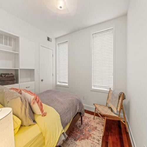 a bedroom with a bed and a chair and windows at Bright & Modern Home with Patio in Philadelphia