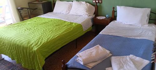 a bedroom with two beds with green and white sheets at Hotel zakros rooms-restaurant in Zákros
