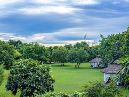 een groene tuin met een huis en bomen bij Aahana The Corbett Wilderness in Rāmnagar