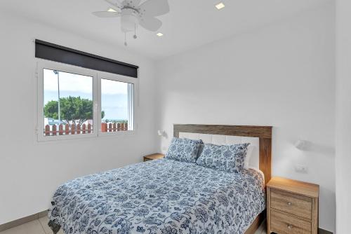 a bedroom with a bed with a blue comforter and a window at Casarossa in Maspalomas