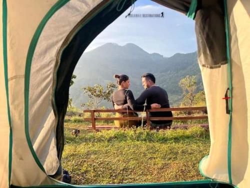 Ein Mann und eine Frau sitzen auf einer Bank in einem Zelt in der Unterkunft Abimansala Resort in Hunnasgiriya