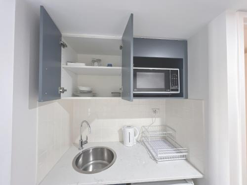 uma pequena cozinha com um lavatório e um micro-ondas em Comfy Studio Next to Chatswood Station em Sidney
