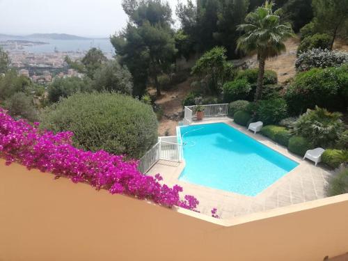 une piscine sur le côté d'une maison avec des fleurs violettes dans l'établissement Bas de villa, vue mer, terrasse, clim, piscine, à Toulon