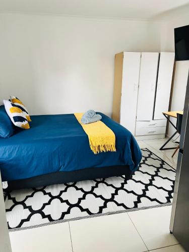 a bedroom with a blue bed and a rug at Private garden guest house in Cape Town