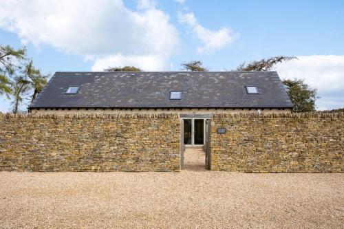 a brick wall with a building behind it at Stone Barn, contemporary barn conversion in Cheltenham