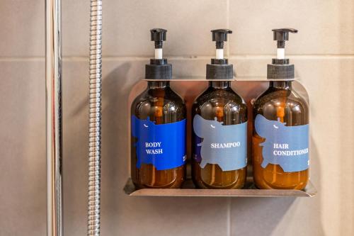 four bottles of honey on a shelf in a bathroom at Blue Hippo & Red Crocodile Hotel in Bangna