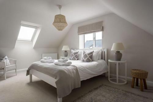 a white bedroom with a bed with towels on it at Stone Barn, contemporary barn conversion in Cheltenham