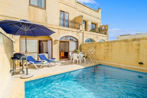 a pool with chairs and an umbrella next to a building at Ta'Sandrija Pool And Well-Being In Gozo - Happy Rentals in Taʼ Bullara