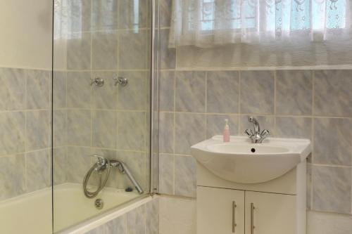 een badkamer met een wastafel, een douche en een bad bij Oppi Plaas in Hazyview