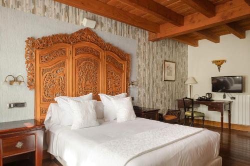 una camera da letto con un letto grande con testiera in legno di Hotel & Spa Etxegana a Zeanuri