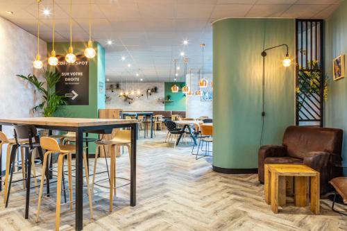 a restaurant with tables and chairs and a green wall at ibis Paris CDG Airport in Roissy-en-France