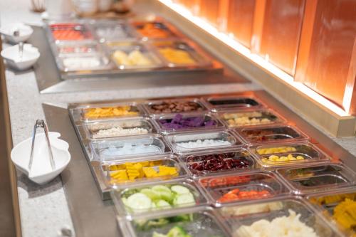 a buffet line with trays of different types of food at Blue Hippo & Red Crocodile Hotel in Bangna