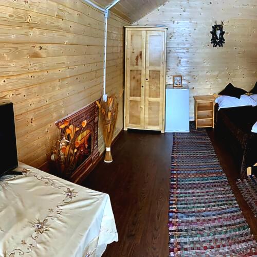 a bedroom with a bed and a room with a fireplace at Căsuțele Camping AliMar in Tîrsa