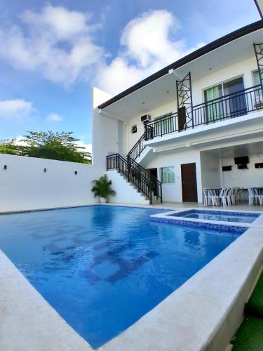 a villa with a swimming pool in front of a house at Sakura's Pool and Leisure Hub in Puerto Princesa City