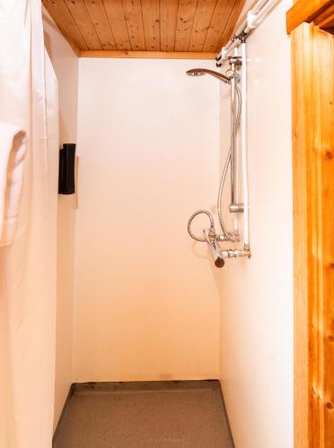 a shower in a bathroom with a white wall at Hótel Eyvindará in Egilsstadir