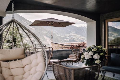 a balcony with a table and chairs and an umbrella at ASTER Boutique Hotel & Chalets in Fügenberg