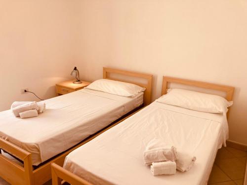 two twin beds in a room with two lamps at Appartamento Maldive Salento piano terra ribassato in Torre Vado
