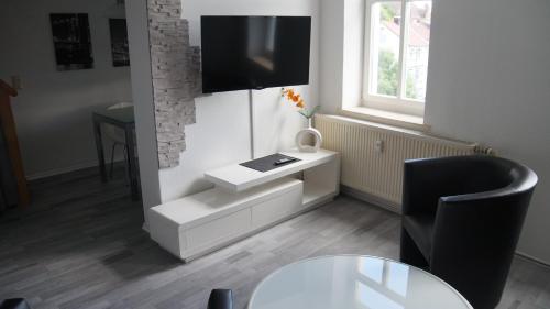 sala de estar con mesa y TV en la pared en Pension Haus Maria, en Mühlhausen